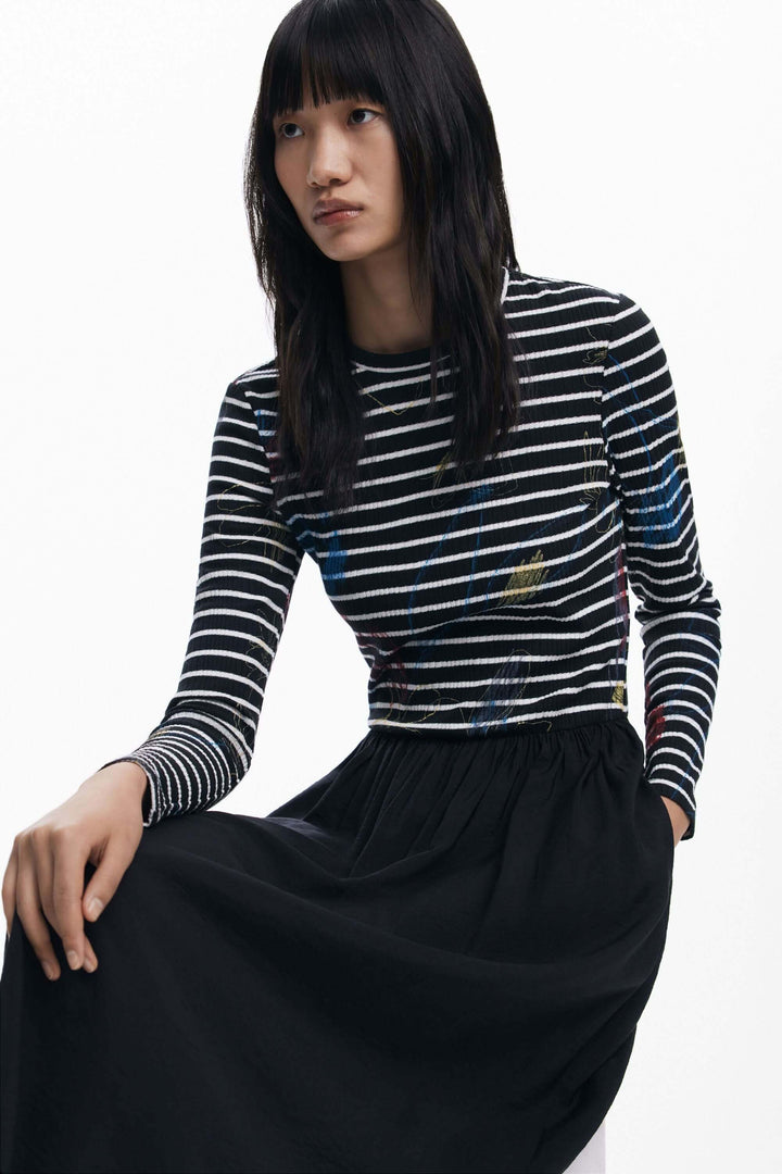 Robe combinée à rayures avec haut graphique et jupe fluide noire, mettant en valeur la silhouette élégante.