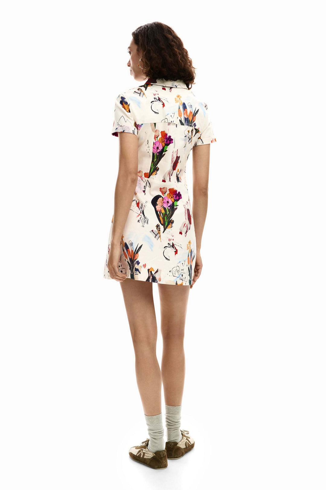 Femme portant une robe courte collage aux motifs artistiques, de dos, montrant la coupe ajustée et la silhouette structurée.