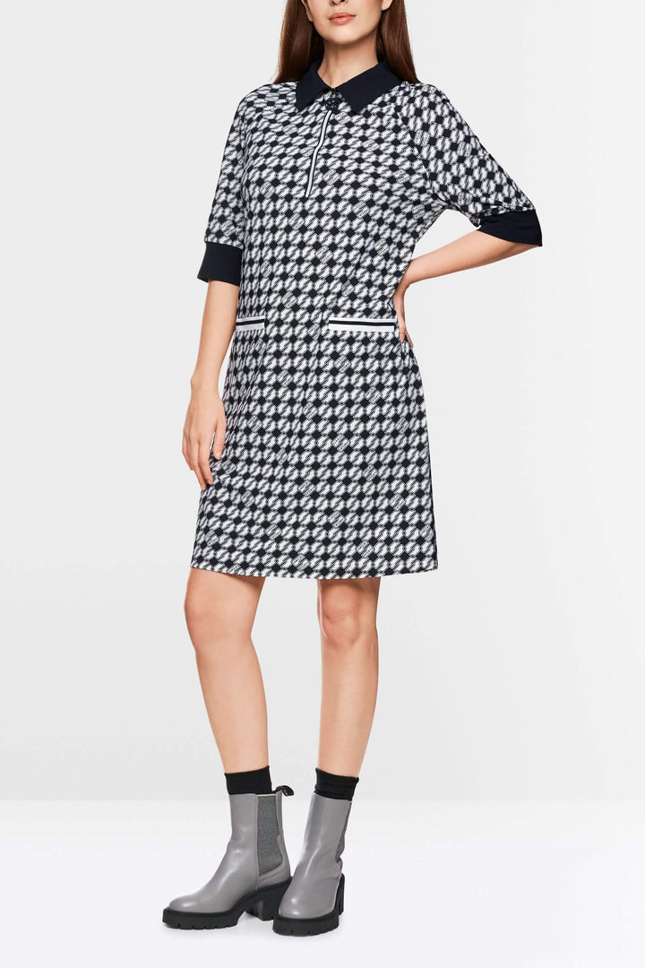 Robe en jersey scuba courte avec imprimé géométrique et bordures contrastantes, portée avec bottines grises.