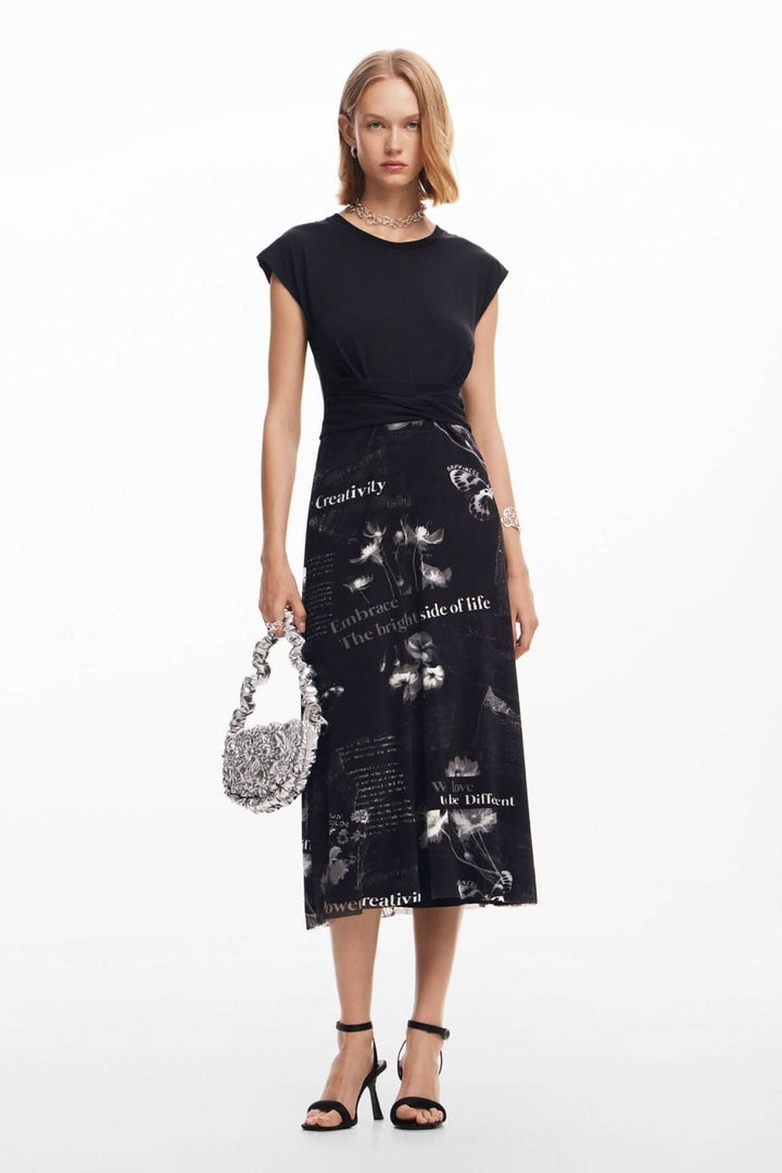 Robe longue noire à manches courtes, encolure ronde, jupe imprimée avec messages inspirants, accompagnée d'un sac élégant.