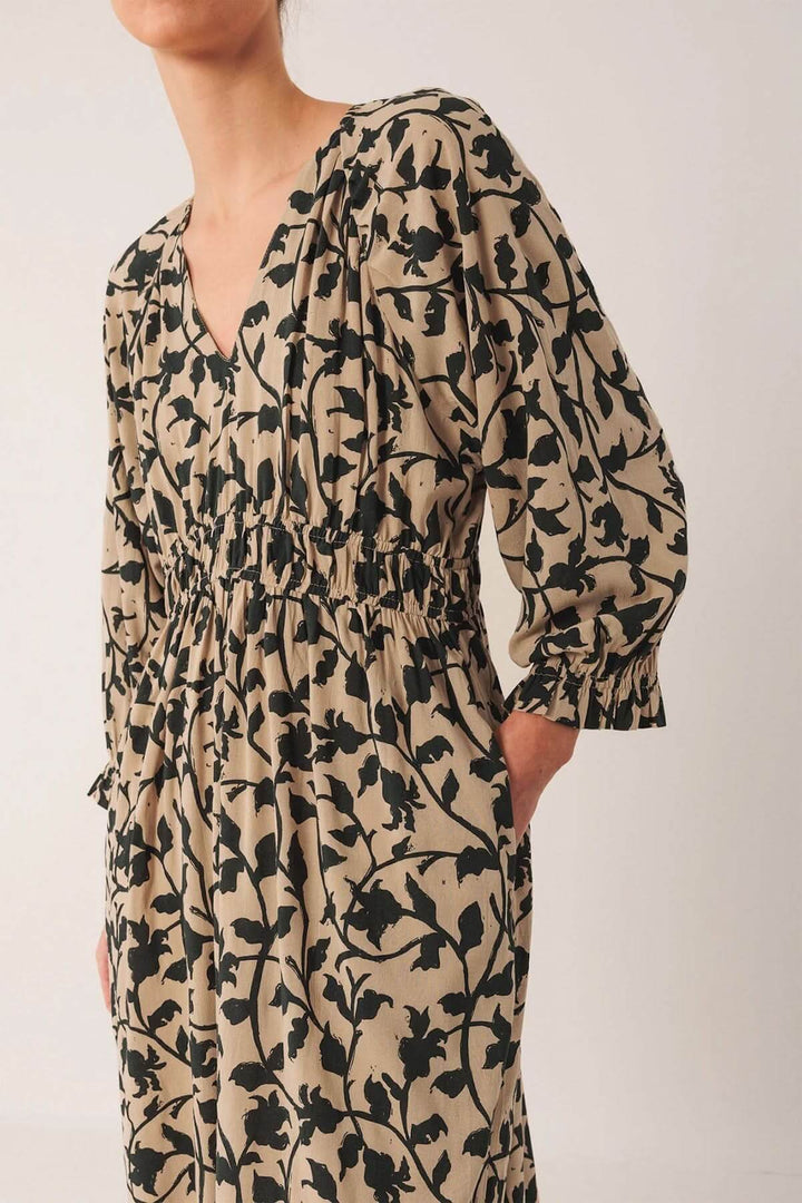 Robe longue fluide avec imprimé botanique, décolleté en V et taille froncée élégante, mettant en valeur la silhouette féminine.