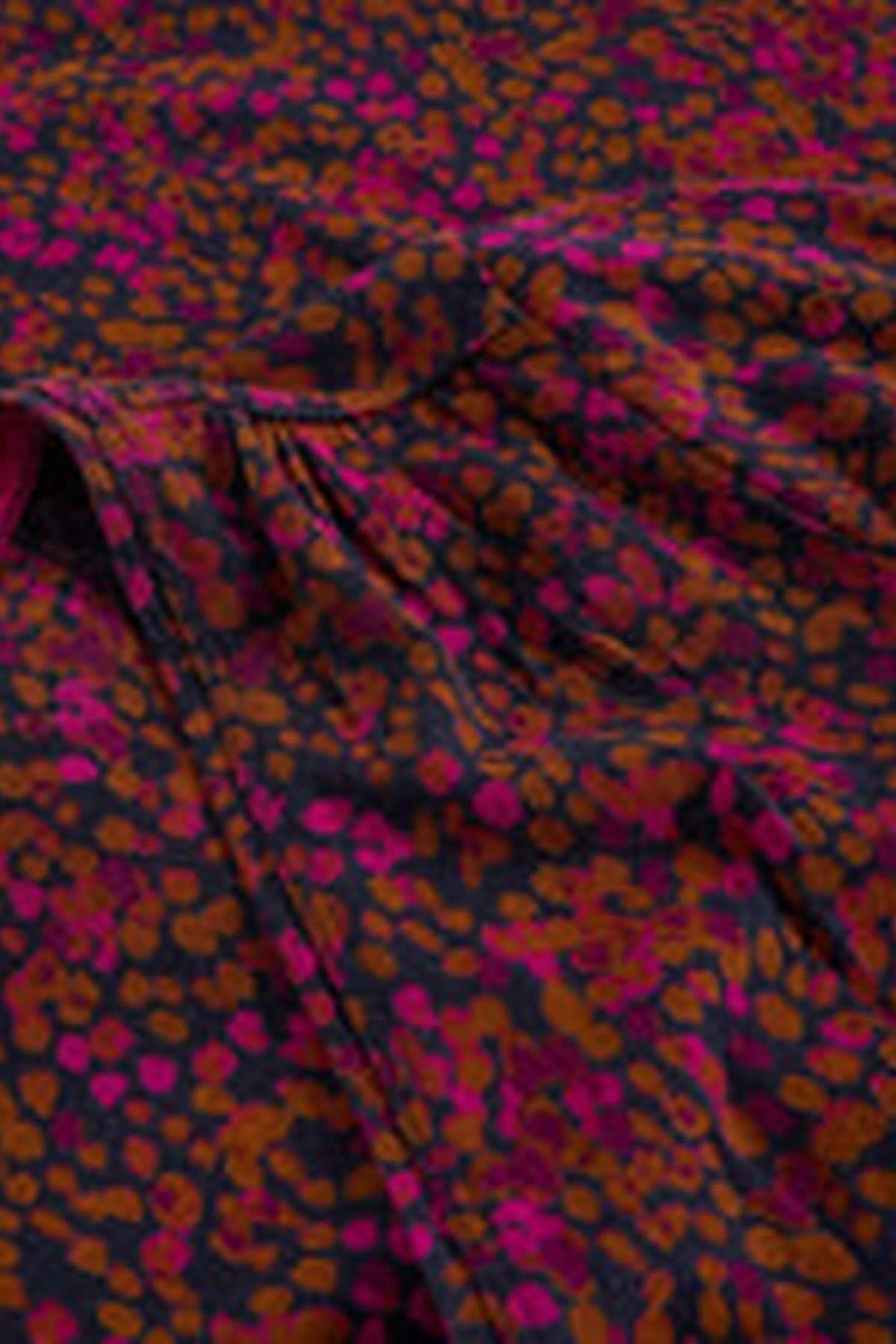 Gros plan sur le tissu de la robe midi en jersey col en V avec motif coloré et effet de fronces pour la silhouette féminine.