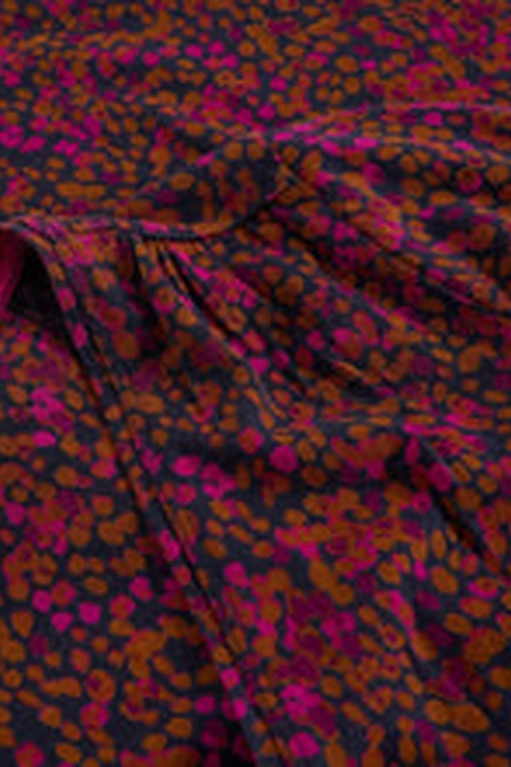 Gros plan sur le tissu de la robe midi en jersey col en V avec motif coloré et effet de fronces pour la silhouette féminine.