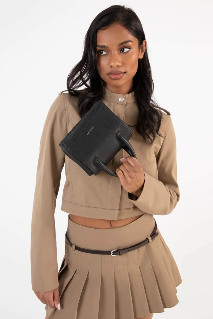 Femme portant une sacoche Adelmicro vegan noire avec des poignées, vêtu d&