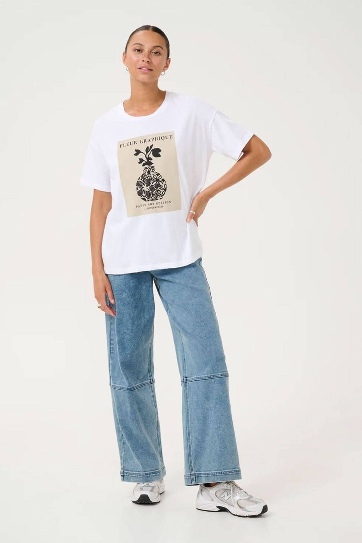 T-shirt blanc avec imprimé artistique ananas, associé à un jean décontracté pour un look moderne.