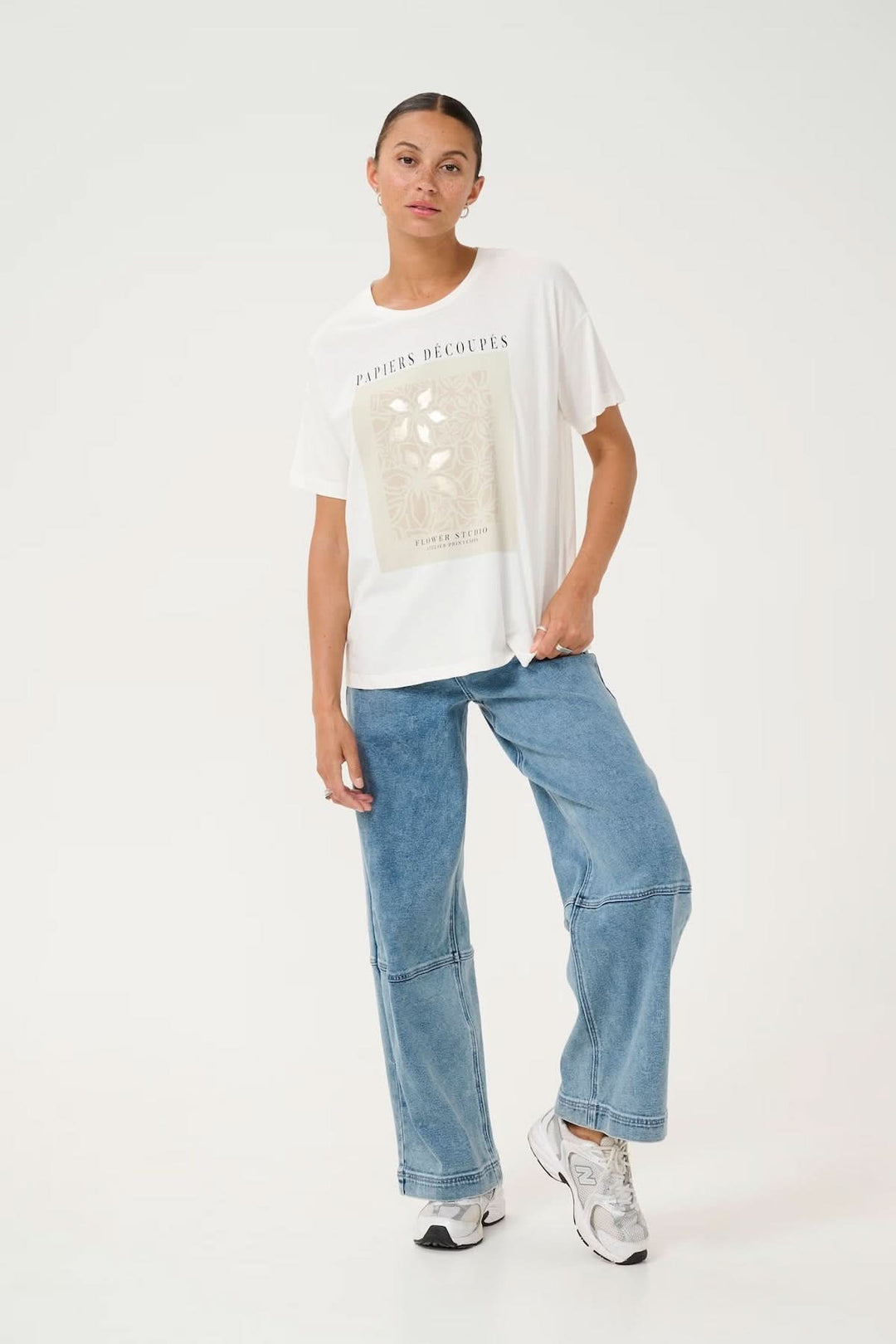 T-shirt artistique à imprimé floral, coupe décontractée, porté avec un jean bleu, look moderne et créatif.