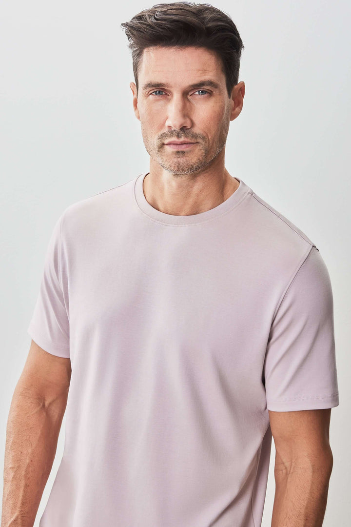Homme portant un t-shirt moderne à manches courtes de couleur pêche, style minimaliste et élégant.