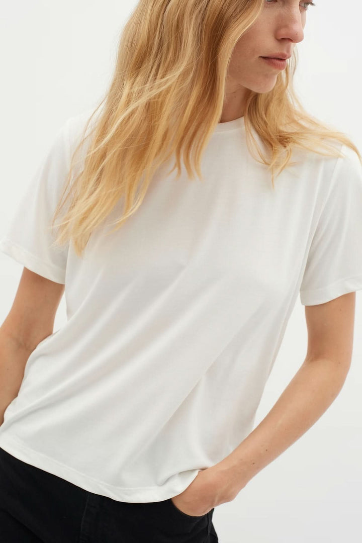 T-shirt Liliana, femme portant un t-shirt blanc à coupe droite, encolure ronde et manches courtes, essentiel pour une garde-robe minimaliste.