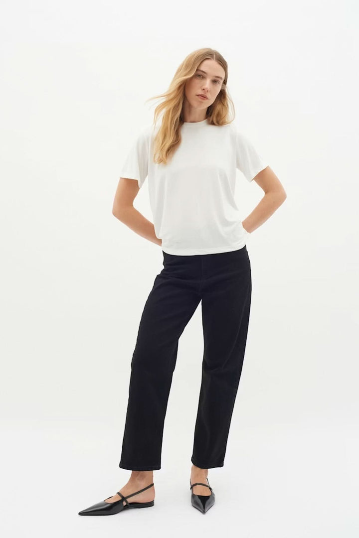 Femme portant un T-shirt Liliana blanc, coupe droite, manches courtes, encolure ronde, style moderne et épuré.