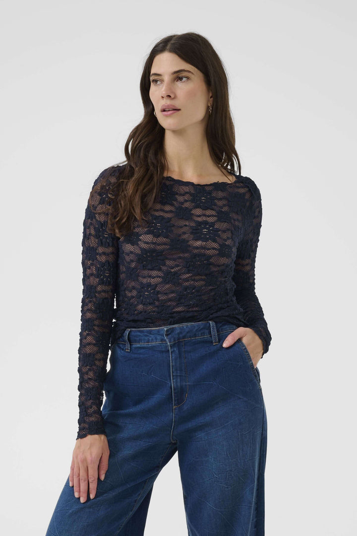 T-shirt Maddie en dentelle, manches longues, coupe ajustée, femme portant un jean, allure féminine et sophistiquée.