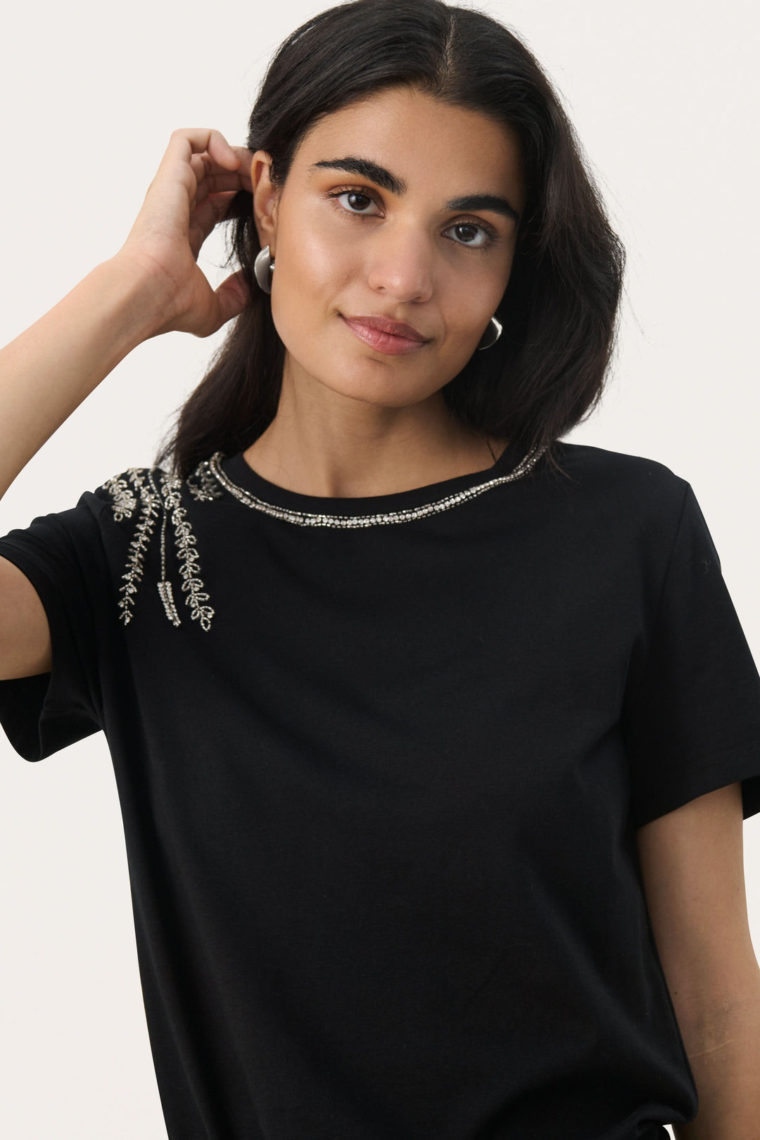 T-shirt noir à col rond avec broderies argentées et perles, élégant et sophistiqué.