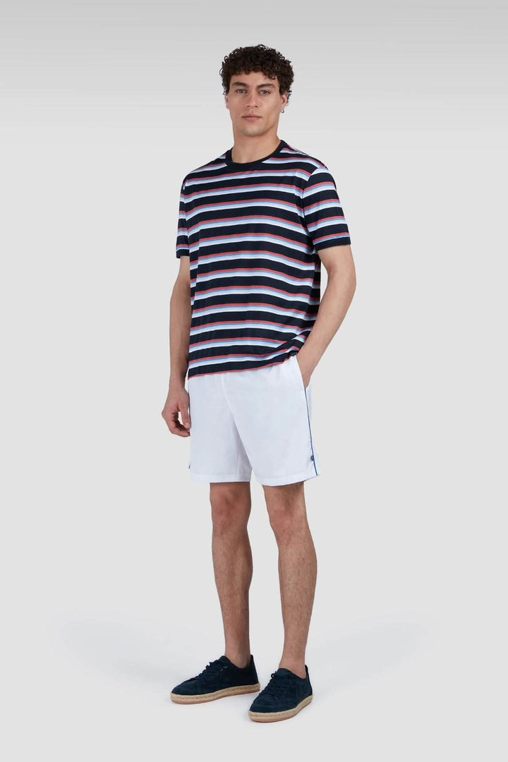 Homme portant un t-shirt à rayures multicolores avec un short blanc, style décontracté.
