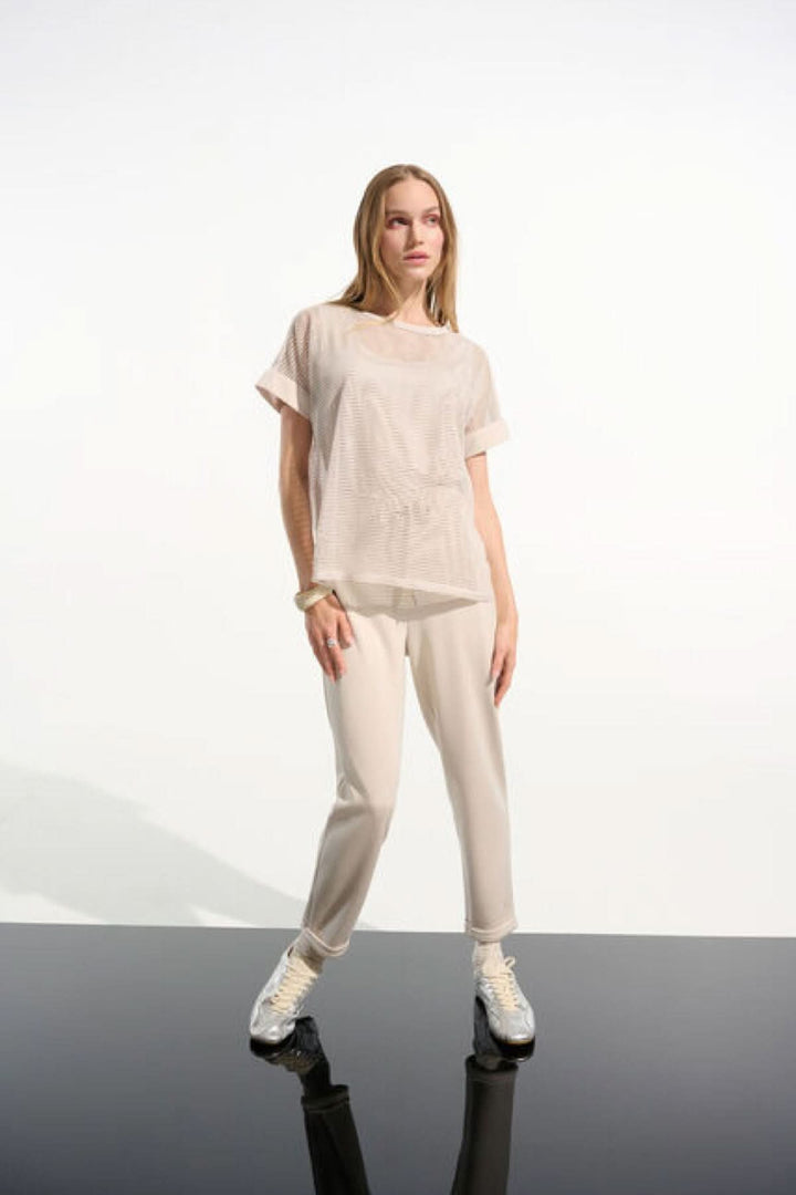 Modèle portant un T-shirt ajouré fluide avec manches courtes et ourlet droit, style moderne et décontracté.