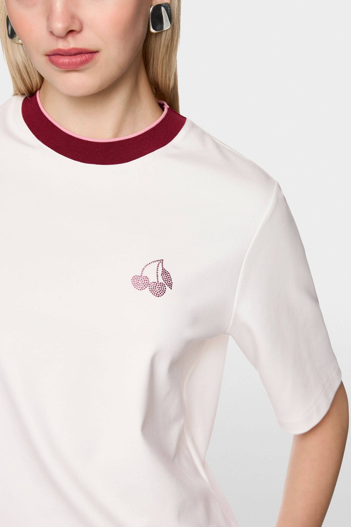 T-shirt classique avec col contrasté et logo cerise brodé, manches courtes, porté par mannequin. Coupe droite et en coton doux.