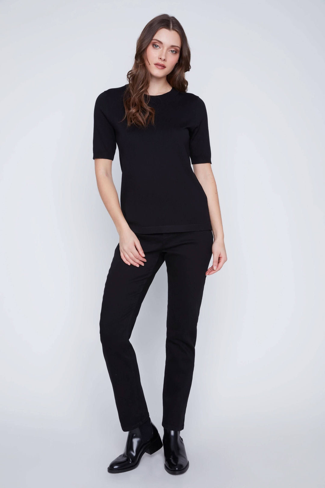 Femme portant un T-shirt classique noir à manches courtes avec coupe droite, idéal pour un look minimaliste et élégant.