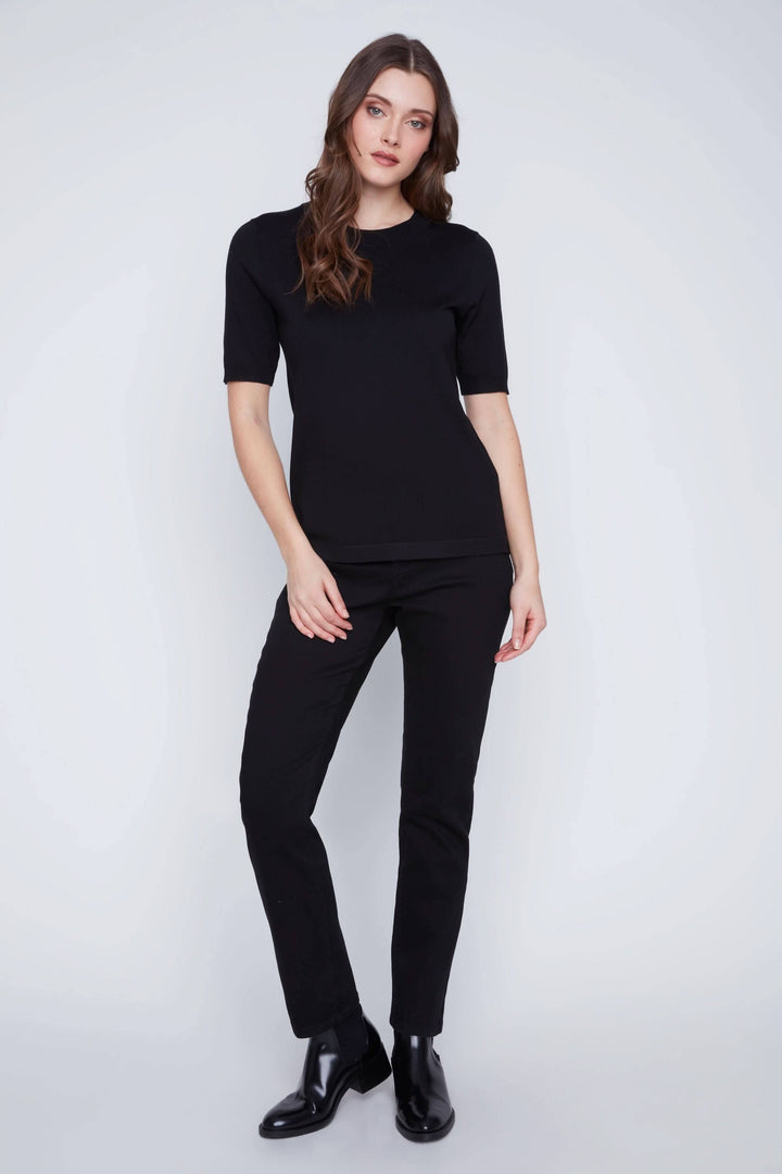 Femme portant un T-shirt classique noir à manches courtes avec coupe droite, idéal pour un look minimaliste et élégant.