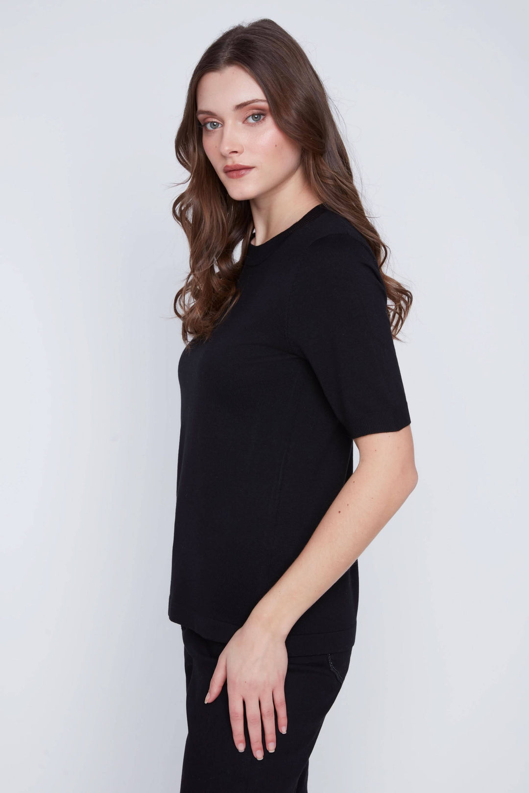 Femme portant un t-shirt classique noir à manches courtes, coupe droite et encolure ronde, style épuré et intemporel.