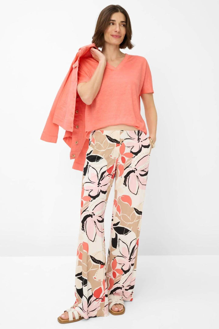Femme portant un t-shirt col V CAELEN en lin avec un pantalon floral, look décontracté et élégant pour l&