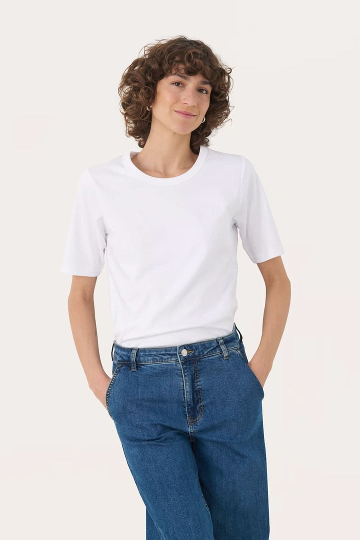 T-shirt à col rond blanc porté par une femme avec des jeans, style décontracté et confortable.