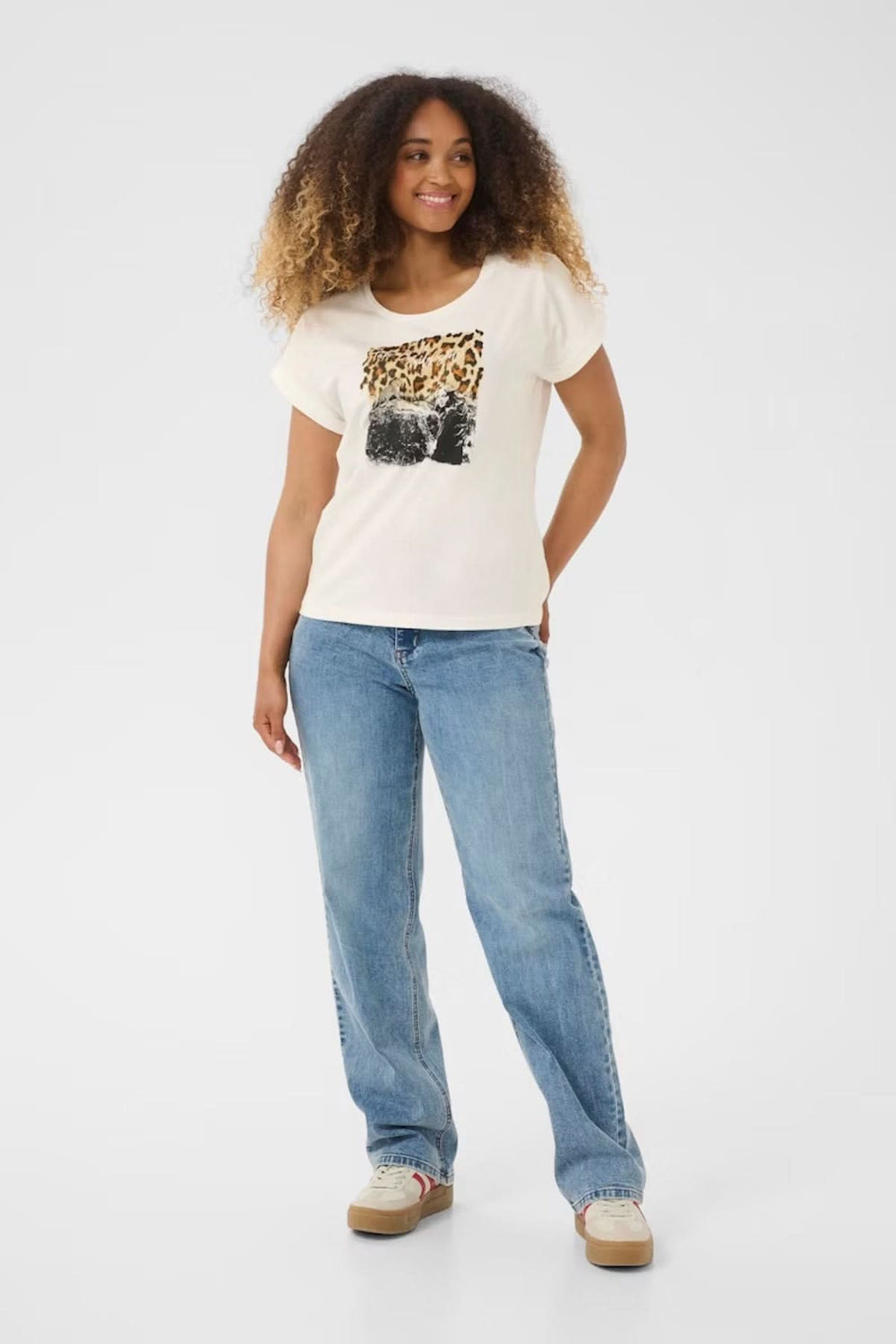 Femme portant un t-shirt à col rond avec imprimé animalier, jean décontracté et look urbain.