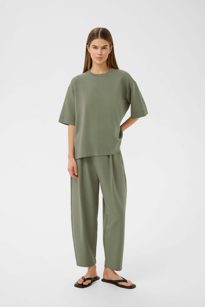 Modèle portant un T-shirt coupe ample Pannie dans un ensemble vert moderne et décontracté.