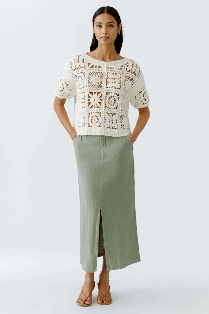 T-shirt crocheté à motifs géométriques porté avec une jupe longue, style bohème chic, pour un look estival élégant.