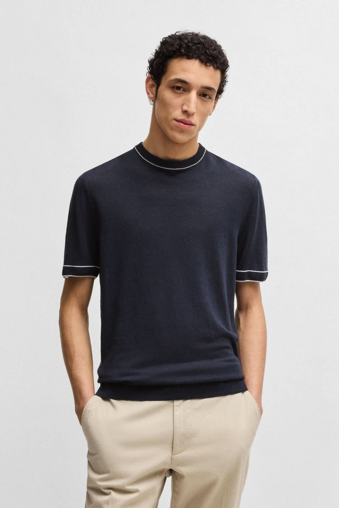 Homme portant un t-shirt en lin noir avec col rond et détails contrastés, associé à un pantalon clair.