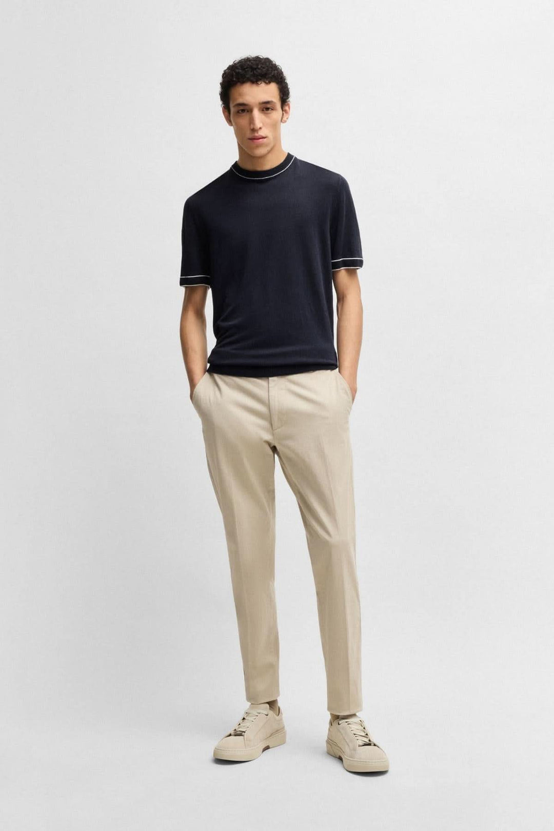 Homme portant un t-shirt en lin noir avec détails contrastés et pantalon chino clair, look décontracté et moderne.