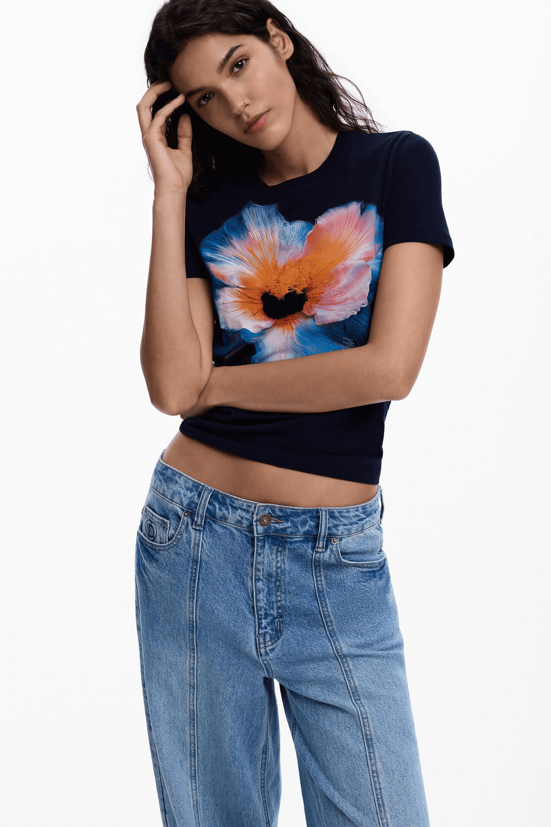 Femme portant un T-shirt grande fleur, motif floral coloré, manches courtes, coupe ajustée, look décontracté et féminin.