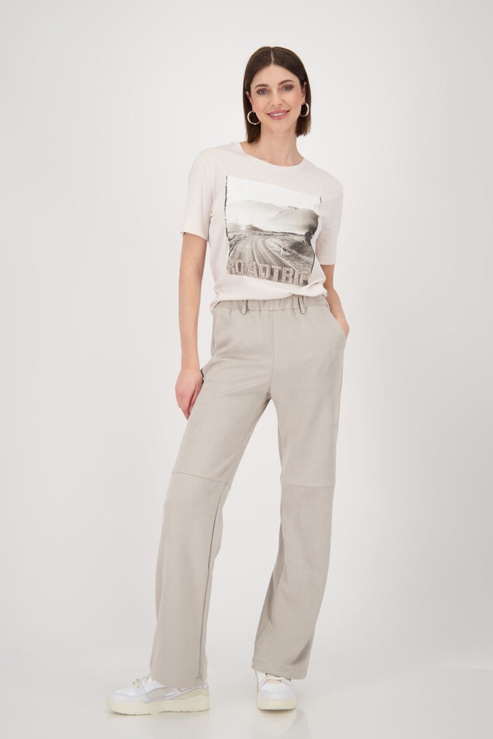 Femme portant un t-shirt imprimé photo 'road trip' avec un pantalon beige et des chaussures blanches.