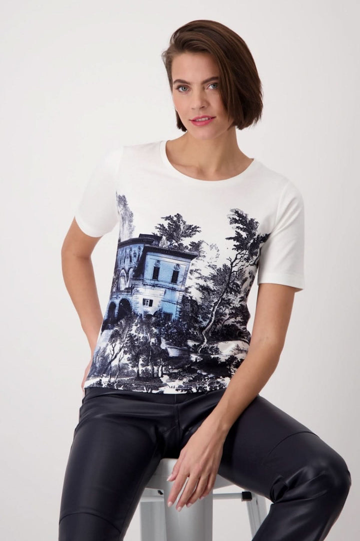 Model wearing a T-shirt with a black and white house print, styled with black leather pants.