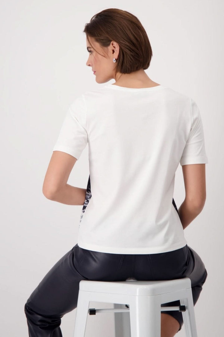 Back view of a model wearing the white "Jardin Anglais" T-shirt paired with black pants, showcasing its casual-chic style.