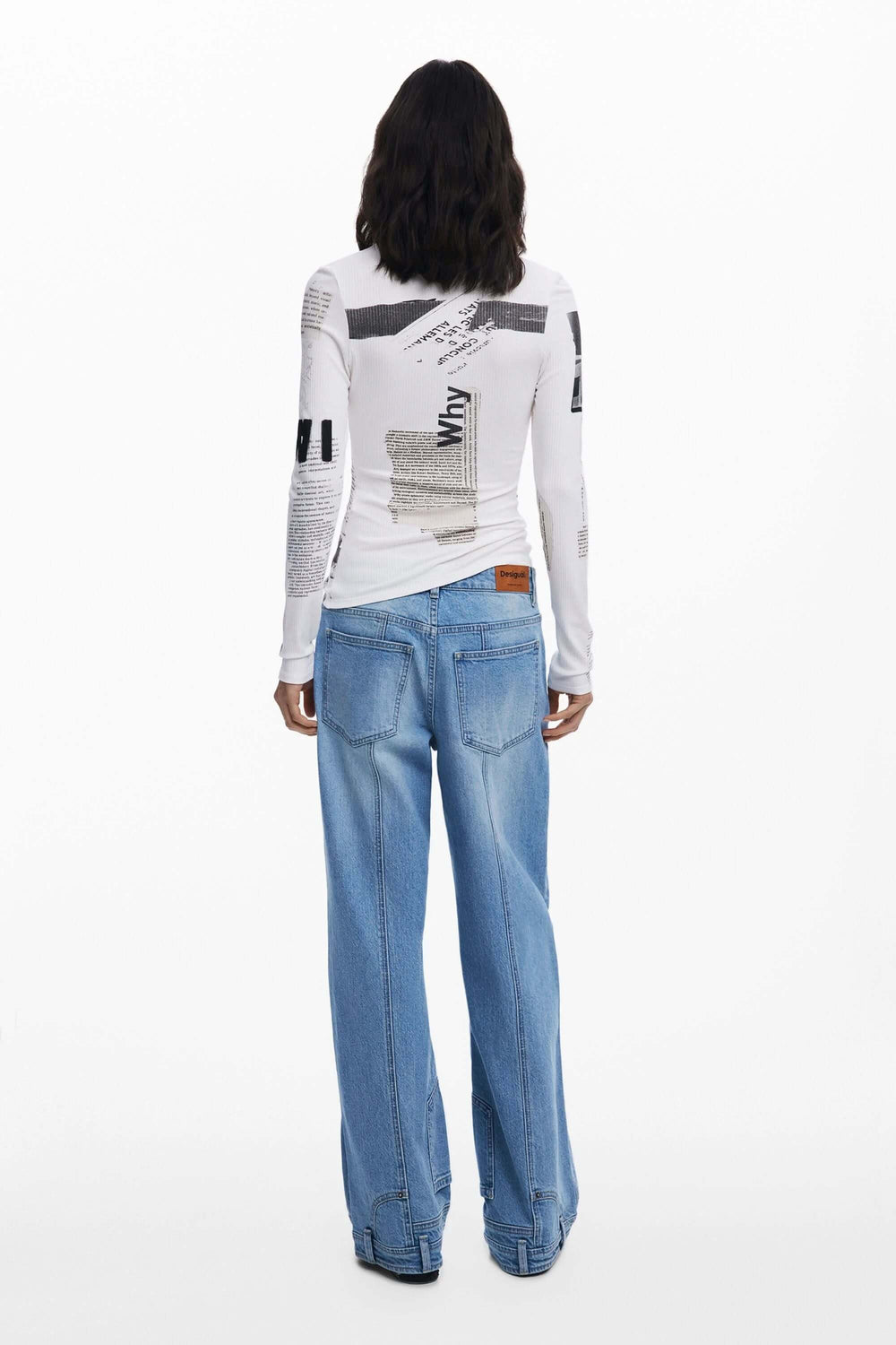 Dos d'une femme portant un T-shirt imprimé typographique, manches longues, avec jean large, style contemporain et moderne.