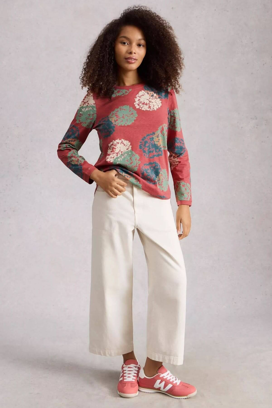 Femme portant un T-shirt à manches longues Clara avec motif, coupe droite et pantalon blanc, confort parfait pour le quotidien.