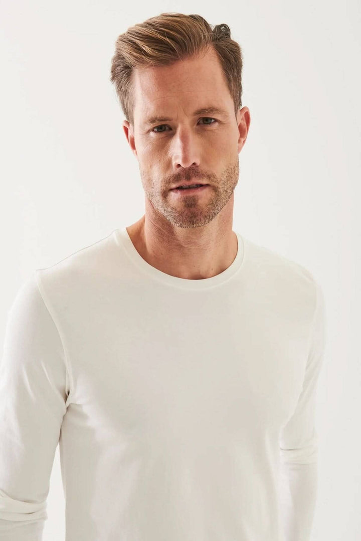 Homme portant un t-shirt blanc à manches longues, col rond en coton Pima péruvien, style décontracté.