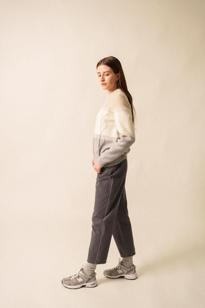 Femme portant un pull en mohair structuré aux teintes grises, associé à un pantalon décontracté et des baskets.