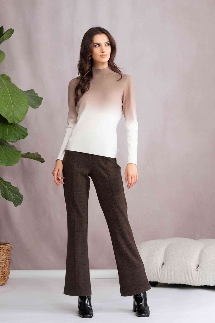 Femme portant un tricot col montant dégradé, manches longues, avec un pantalon marron et des bottes noires, look moderne et élégant.