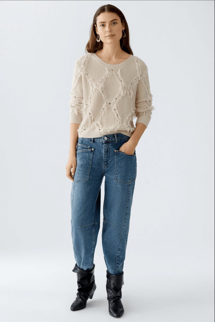 Tricot motif losange avec franges et détails métalliques, style décontracté.