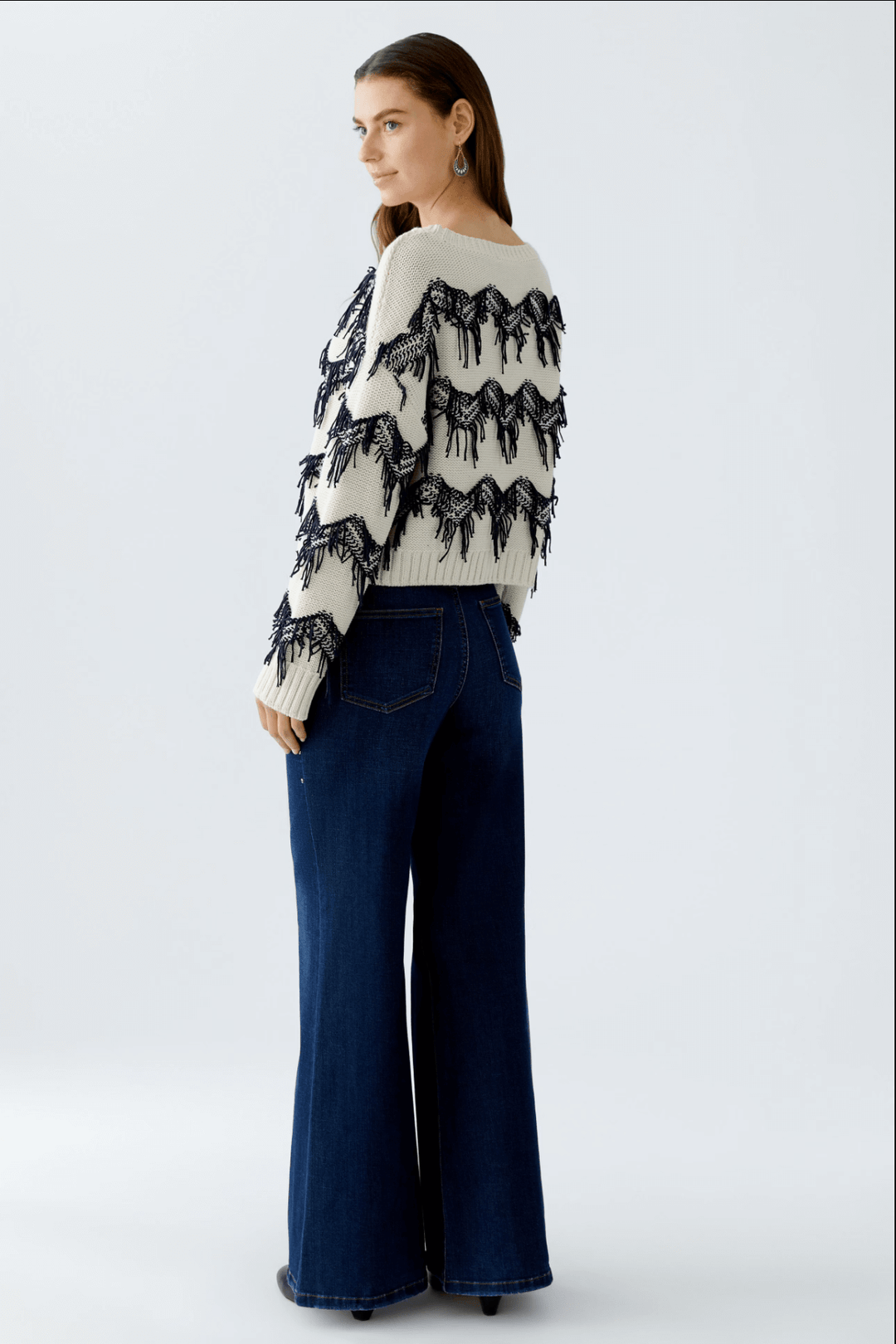 Femme portant un tricot motif zigzag avec franges tricotées et coupe carrée.