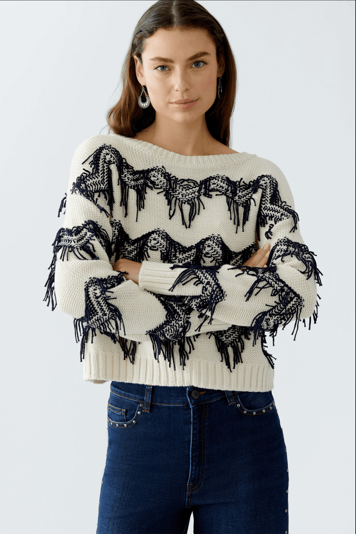 Tricot motif zigzag avec franges, coton, coupe carrée, encolure sous-marine, moderne et décontracté, porté avec pantalon taille haute.