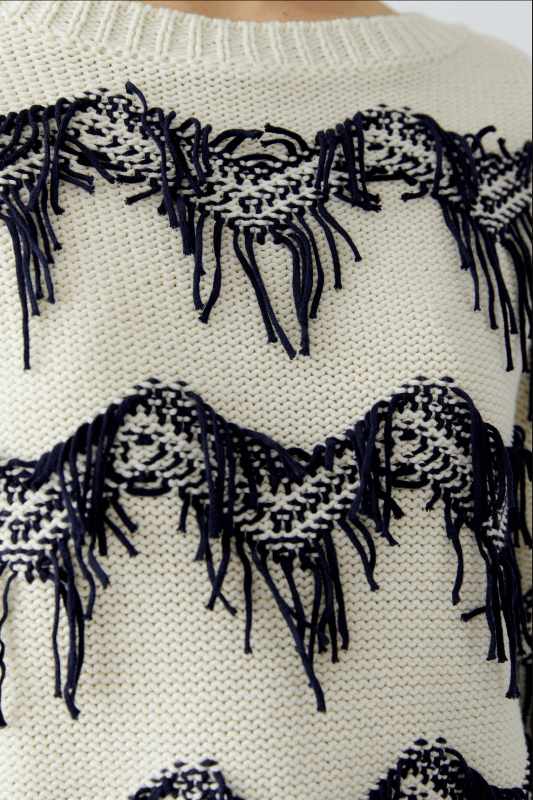 Tricot motif zigzag avec franges tissées à la main, coupe carrée moderne, encolure sous-marine, en pur coton.