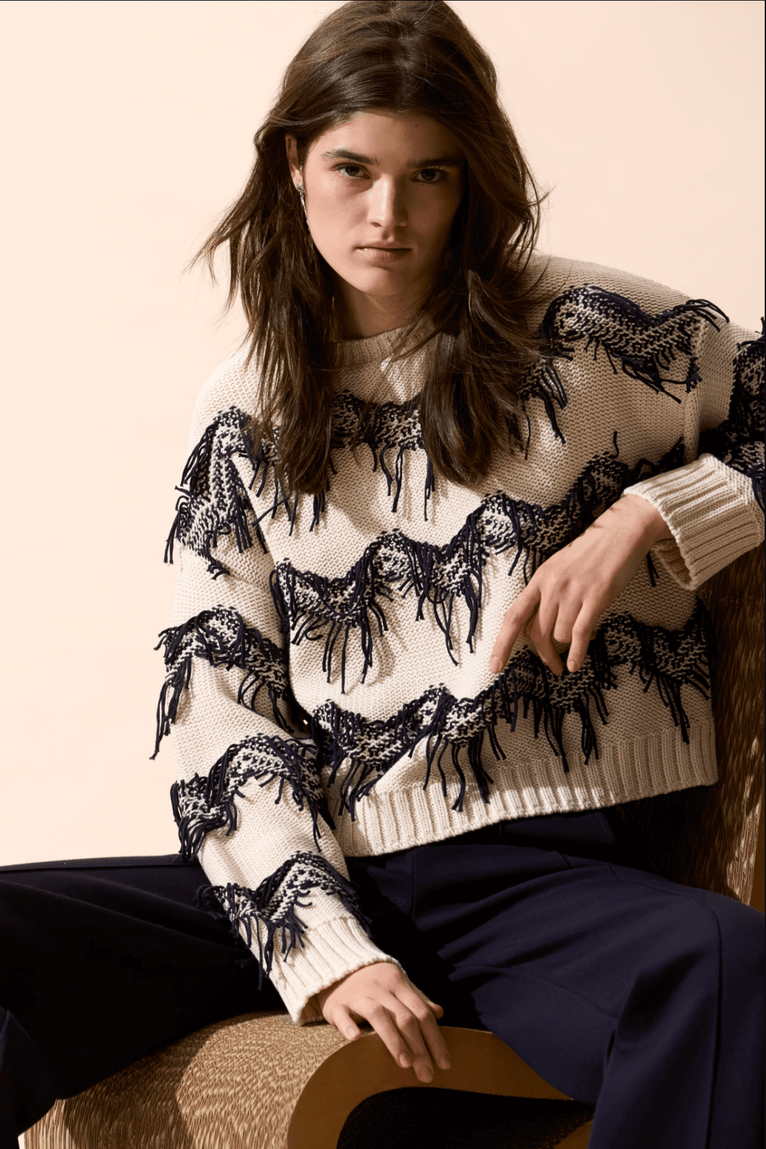 Tricot motif zigzag avec franges coupées à la main, coupe carrée, encolure sous-marine, porté avec un pantalon taille haute.