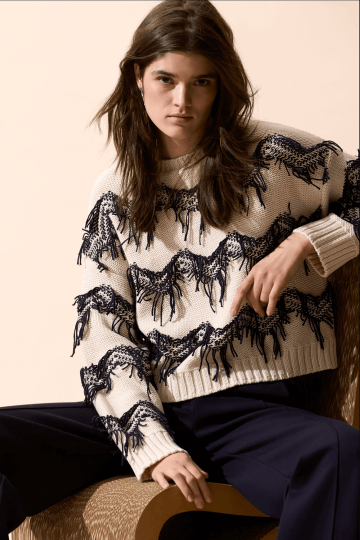 Tricot motif zigzag avec franges coupées à la main, coupe carrée, encolure sous-marine, porté avec un pantalon taille haute.