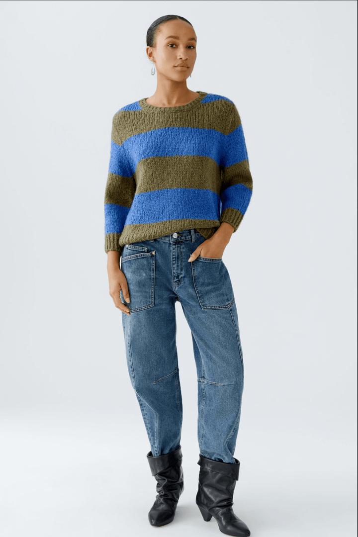 Femme portant un tricot rayures larges avec un jean, style décontracté et moderne, col ras du cou et manches 3/4.