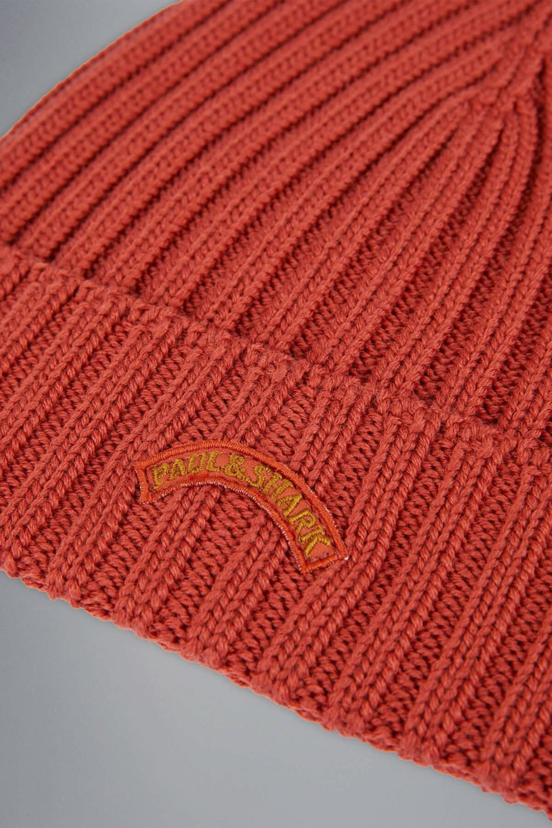 Bonnet en laine côtelée couleur rouge avec logo brodé, parfait pour l'hiver.