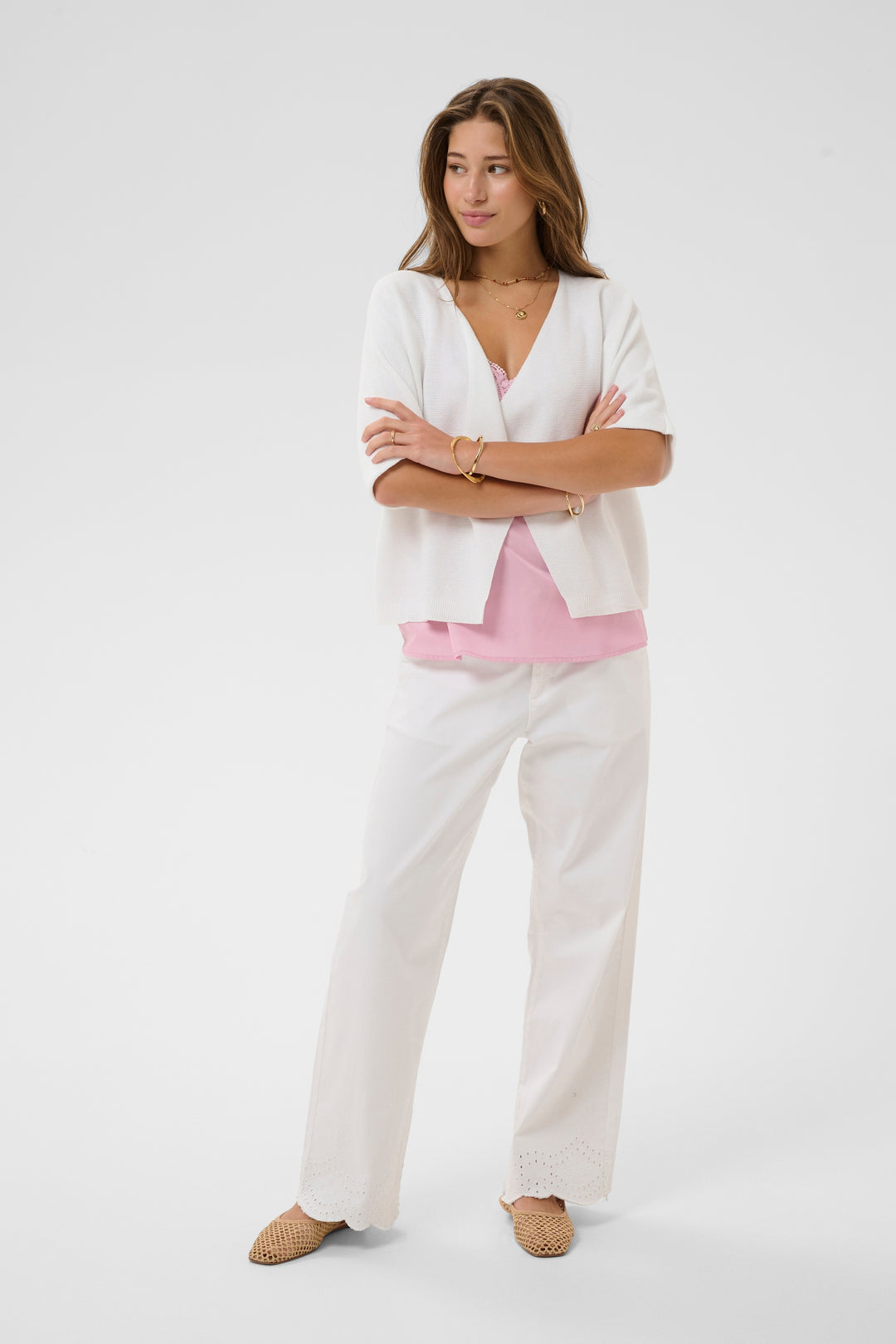 Femme portant la Veste avec manches Sillar blanche, coupe fluide et ouverte, parfaite pour superposer sur un camisole rose.