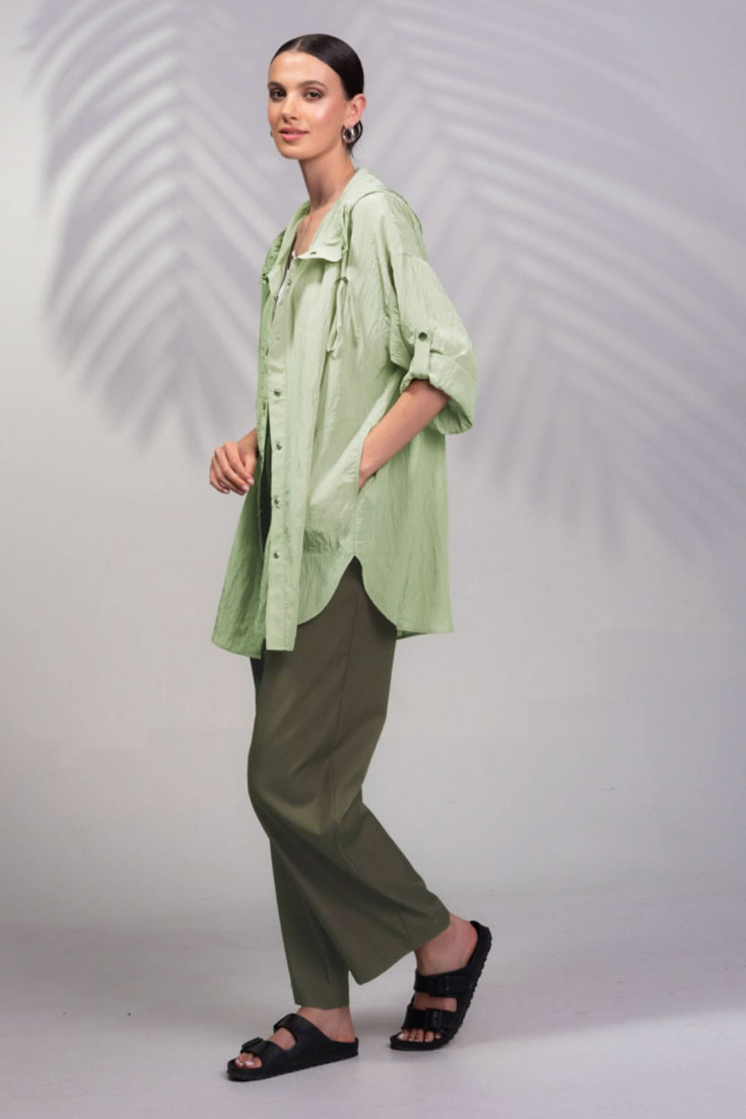 Veste à capuche surdimensionnée en vert portée avec pantalon assorti, style décontracté et poches latérales.