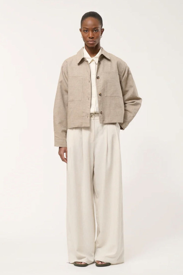 Veste chemise courte sur mannequin avec col chemise, poches plaquées et fermeture boutonnée, alliant décontraction et élégance.