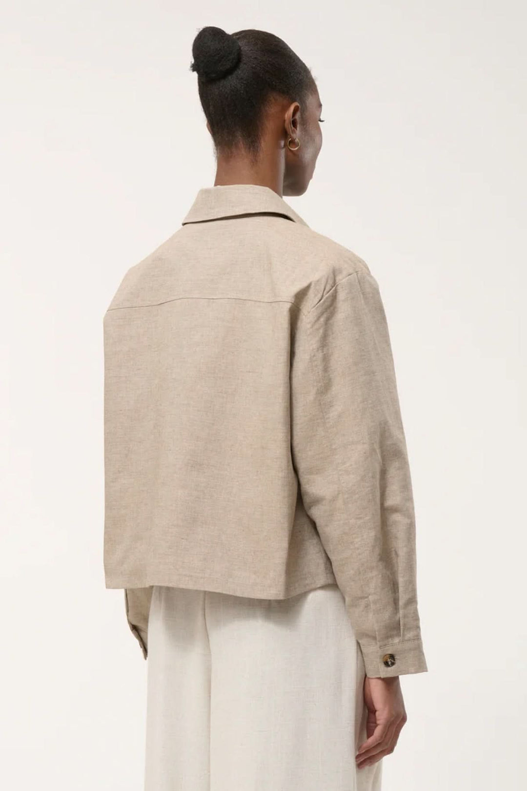 Veste chemise courte beige vue de dos, élégante et utilitaire, avec coupe structurée et poches plaquées.