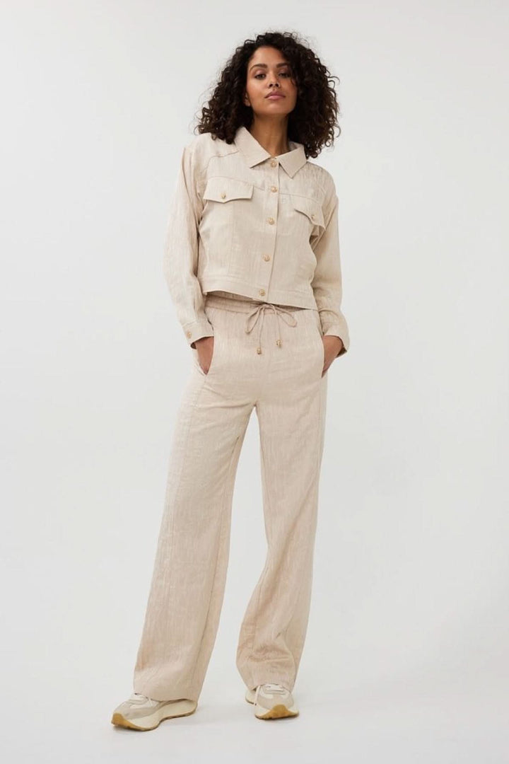 Modèle portant une veste courte en jacquard texturé et un pantalon coordonné, style moderne et élégant.